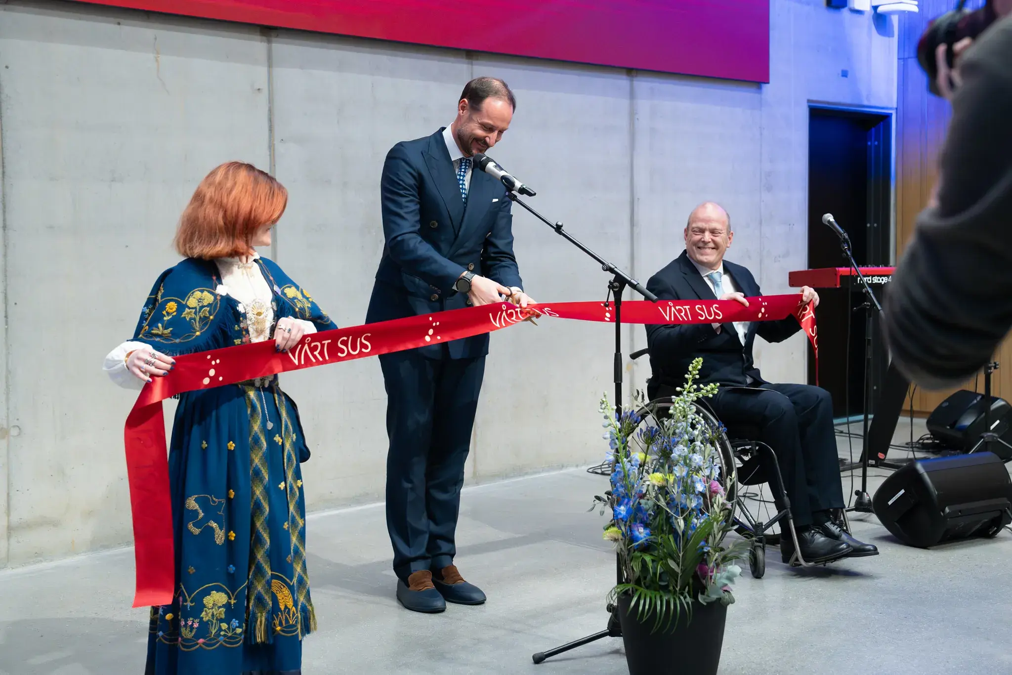 En kvinne som holder et rødt bånd ved siden av en mann i dress