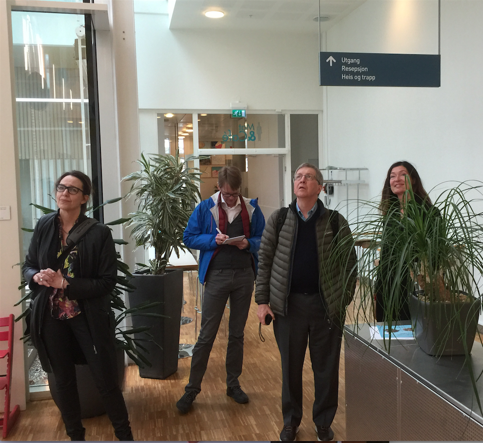 En gruppe mennesker som står i et rom med planter og et skilt