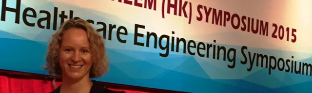 En person som smiler foran et skilt