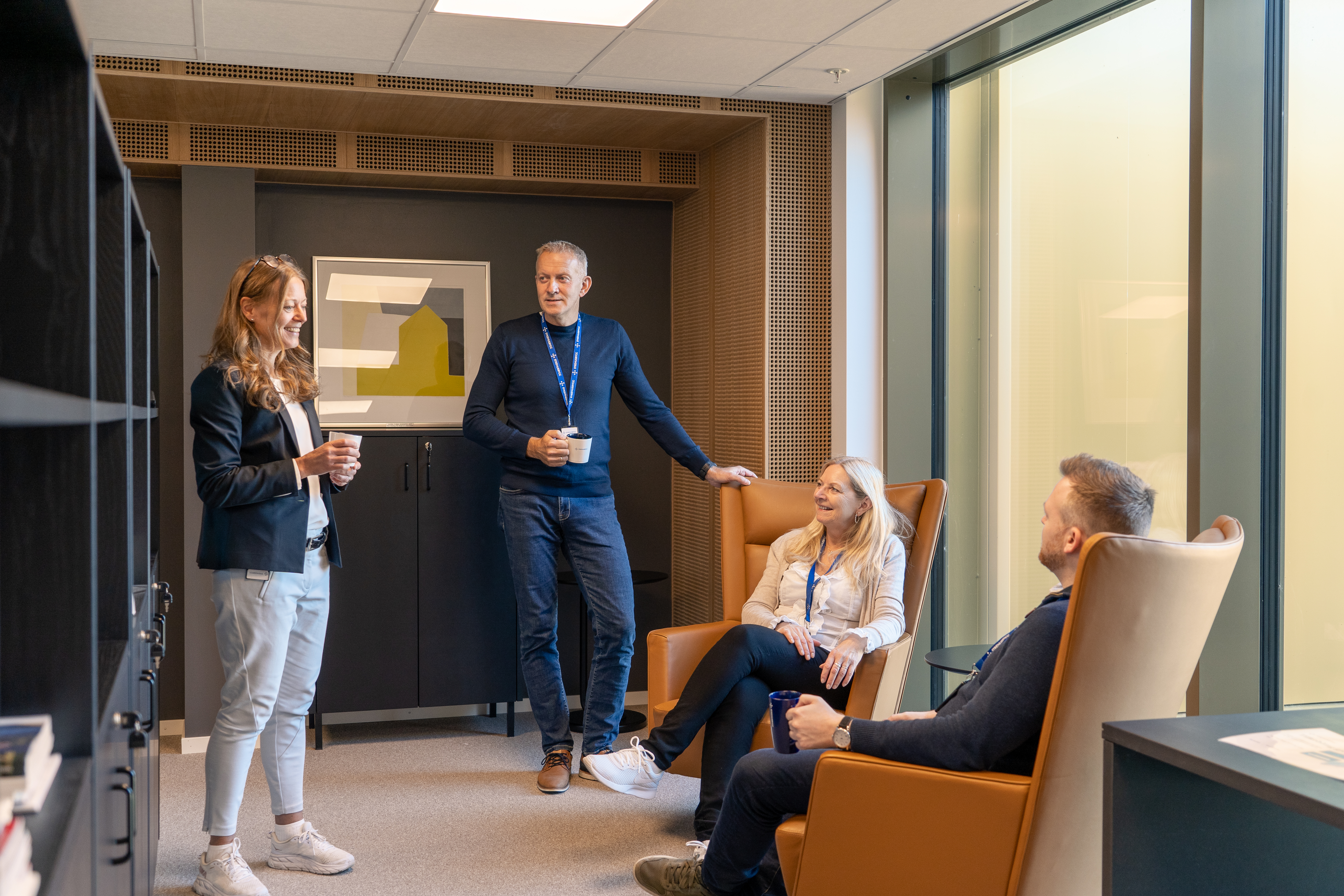 Kvinner og menn konverserer i kontorlokale