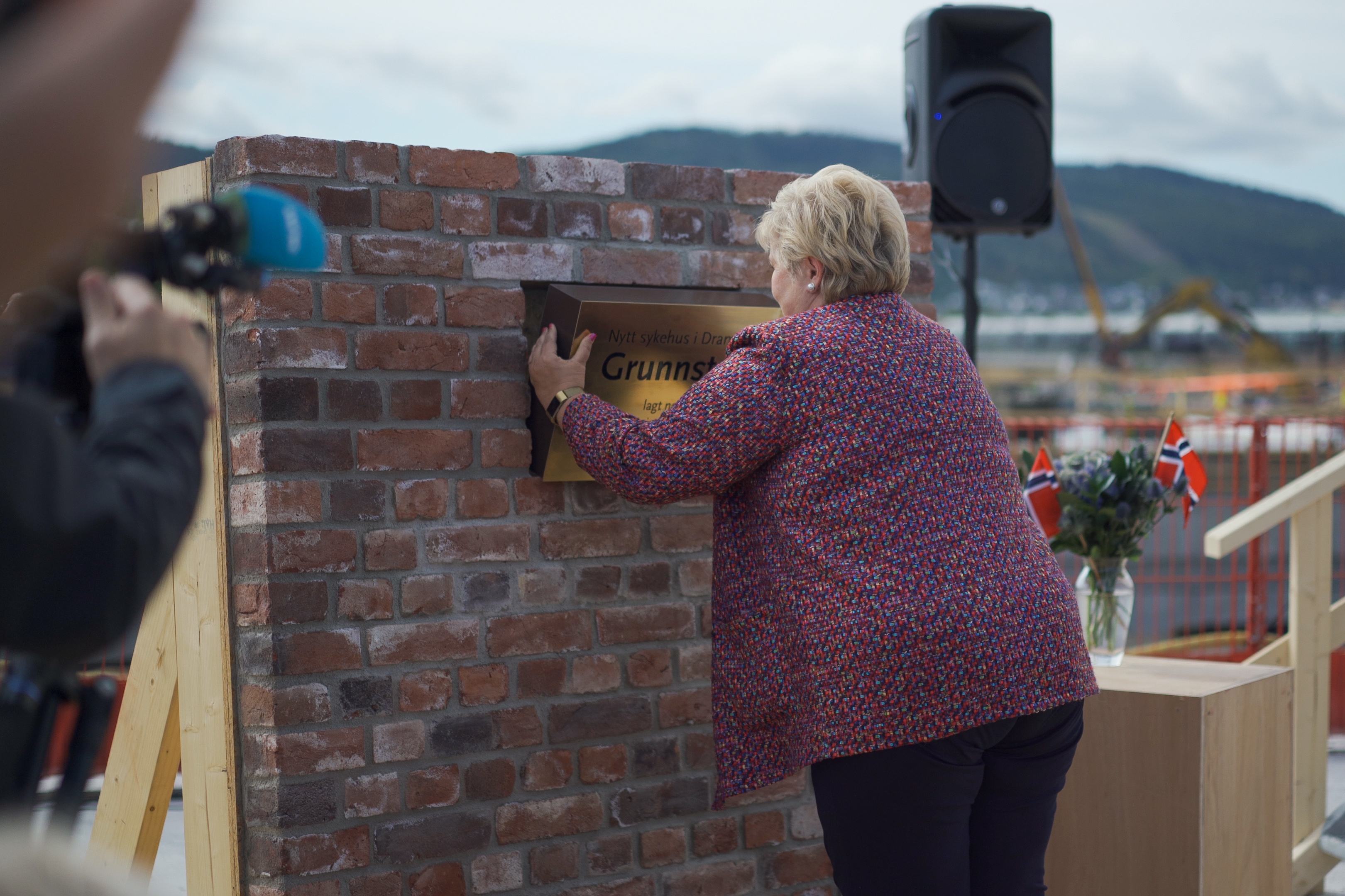 Statsministeren setter messingskrinet inn i teglveggen