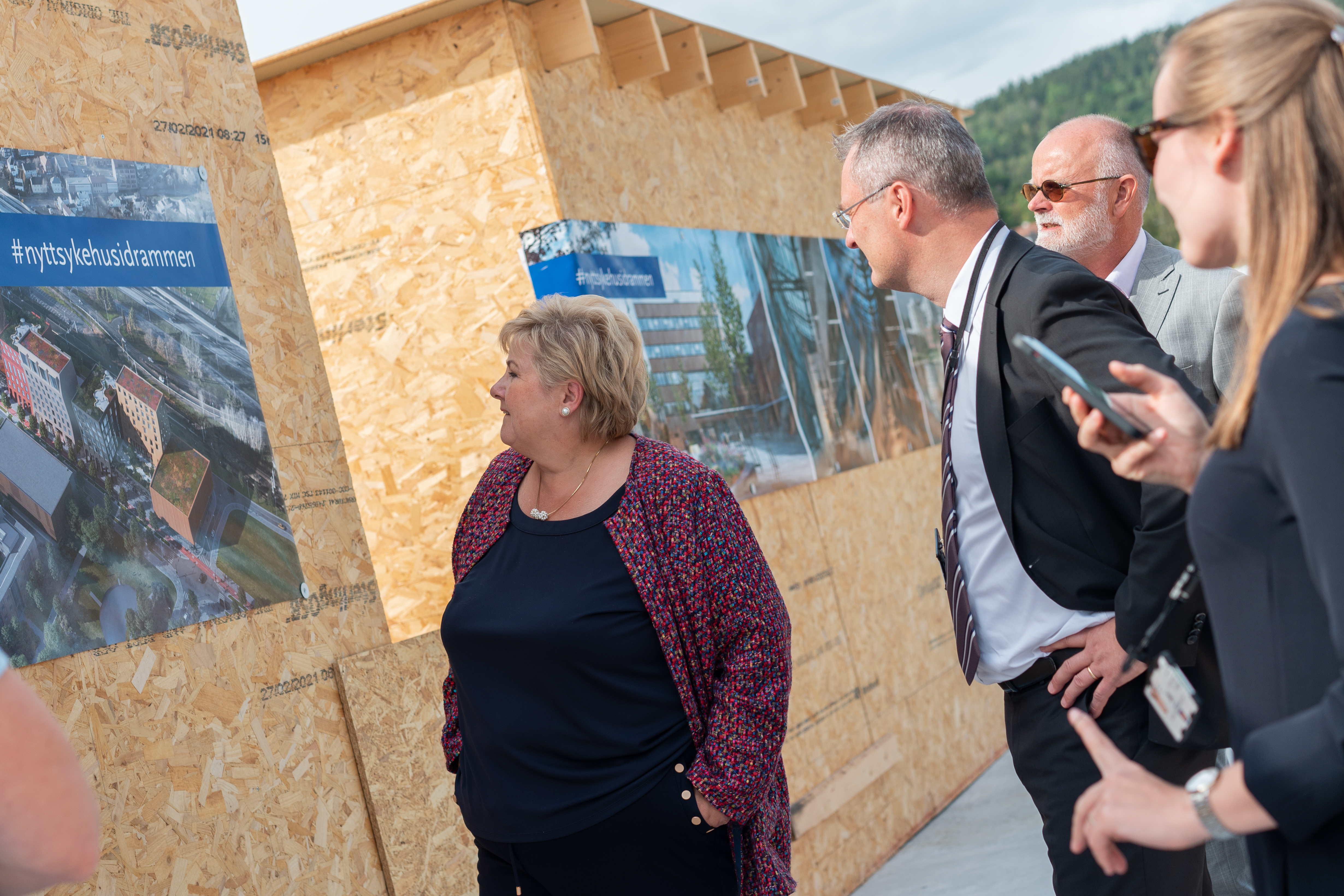 Statsministeren og tre andre ser på vegg med bilde