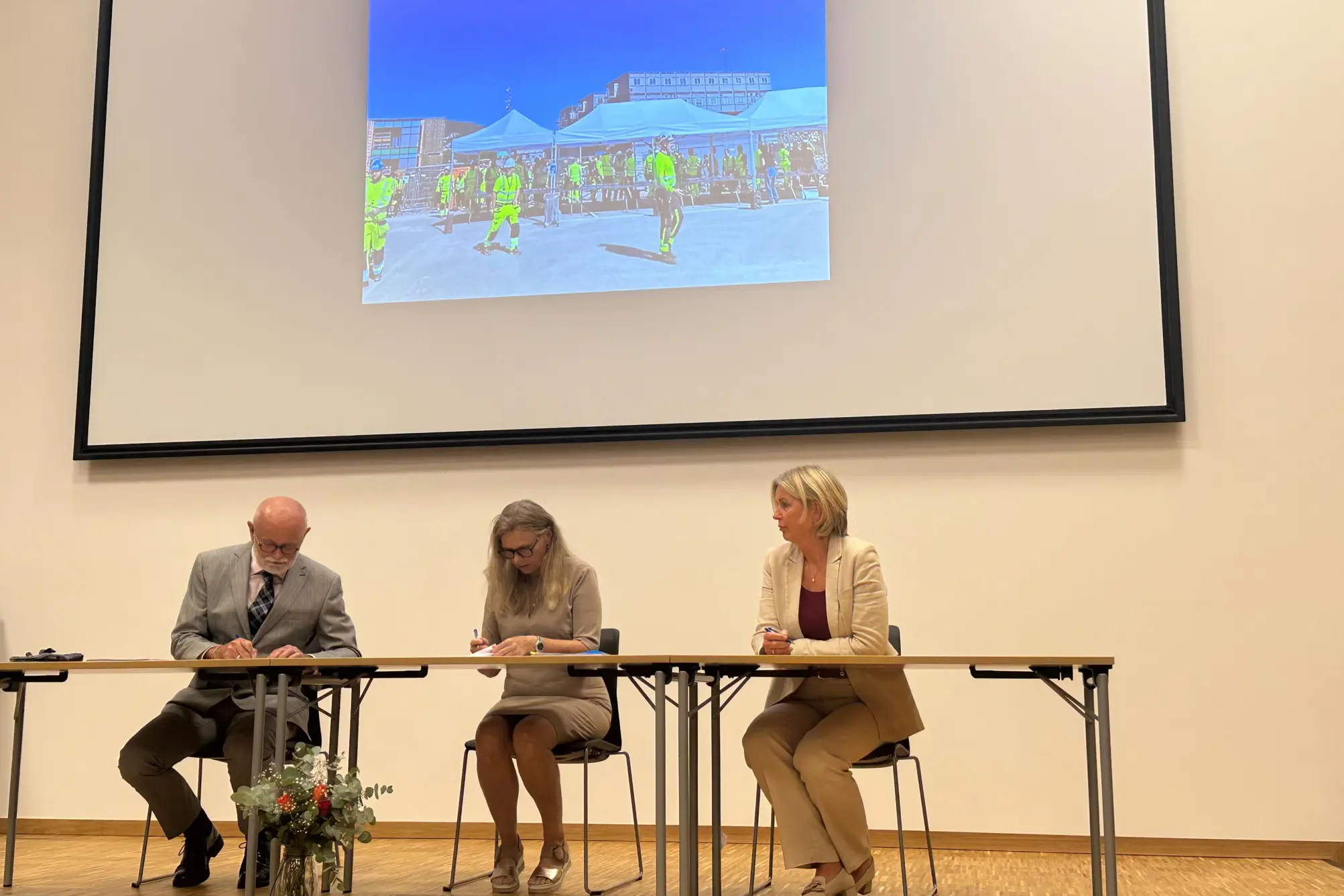 En mann og en kvinne som sitter ved et bord foran en projektorskjerm