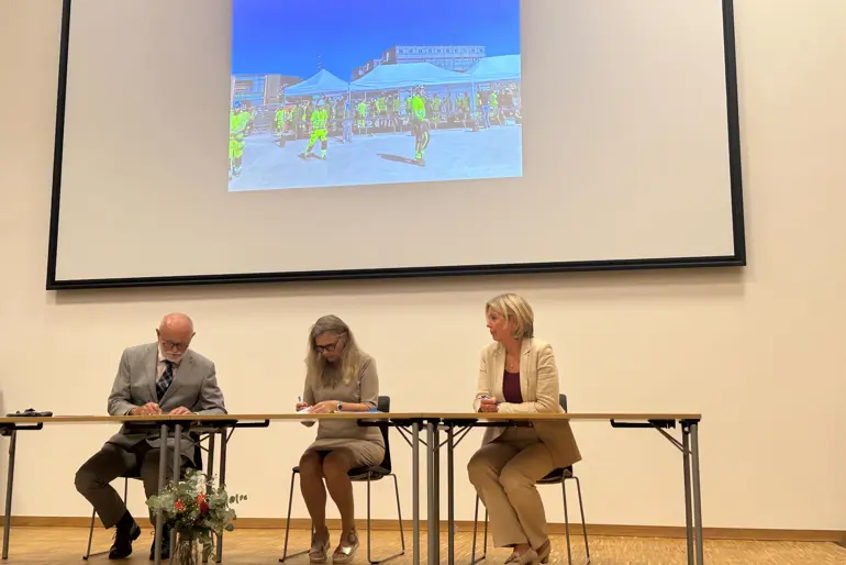 En mann og en kvinne som sitter ved et bord foran en projektorskjerm