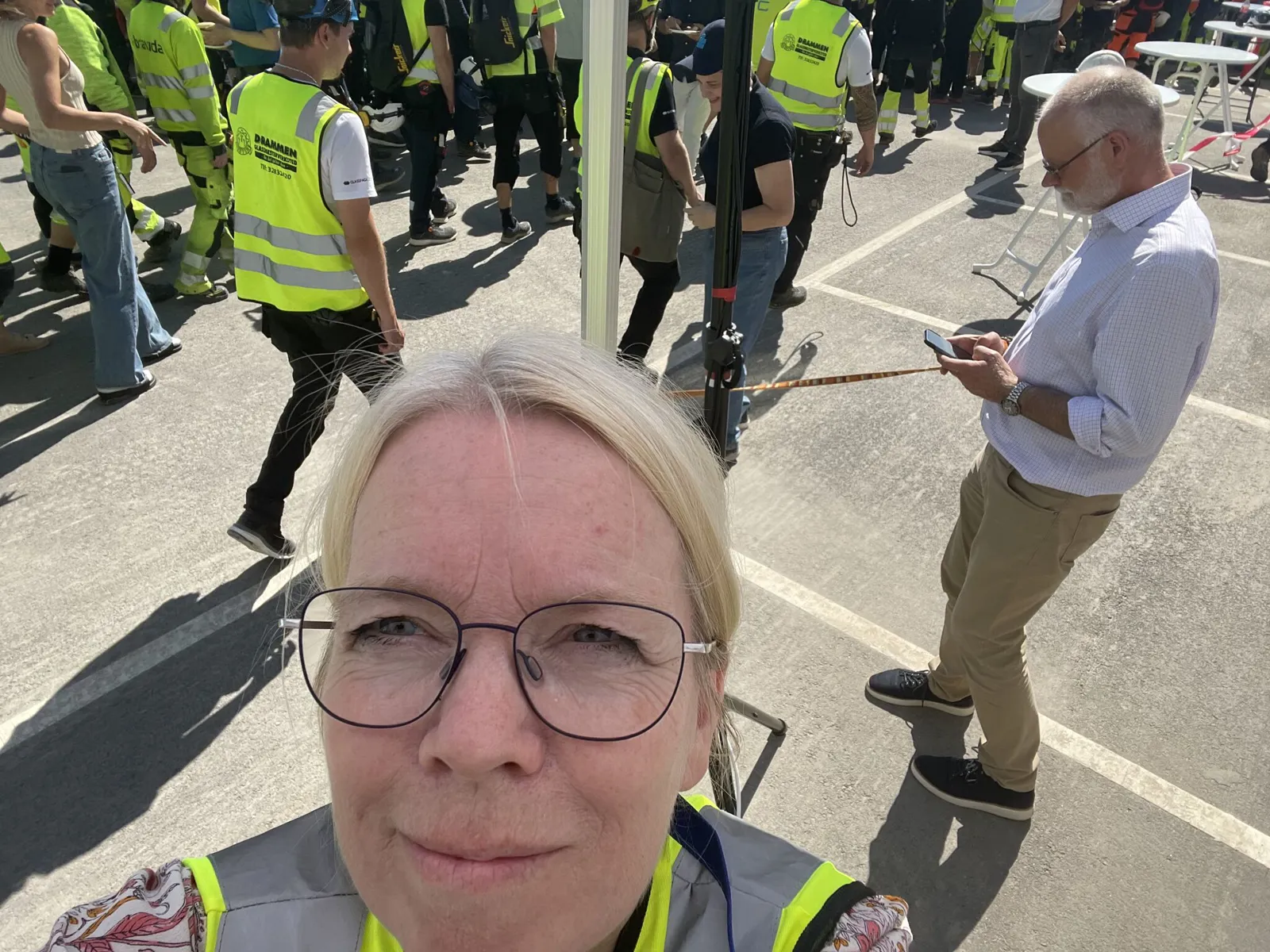 En mann som tar en selfie med en gruppe mennesker i bakgrunnen