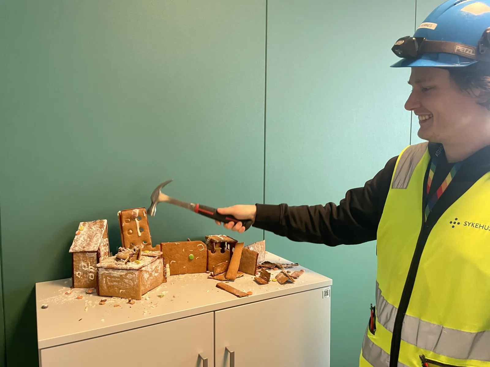 En person i en sikkerhetsvest som holder en hammer og en trekloss