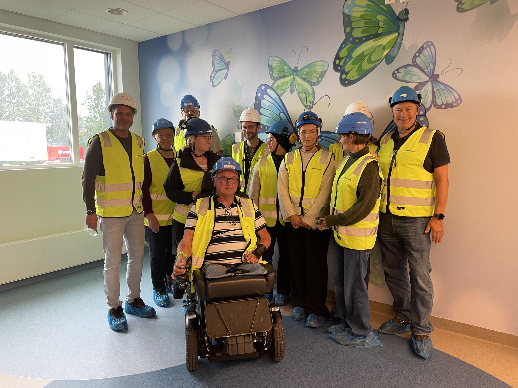 En gruppe mennesker iført sikkerhetsvester og står i et rom