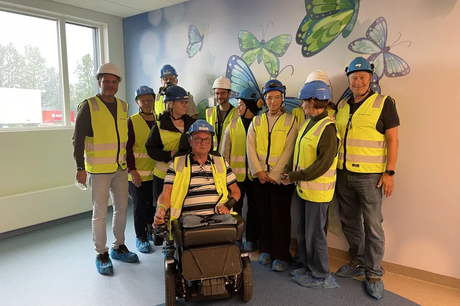 En gruppe mennesker iført sikkerhetsvester og står i et rom