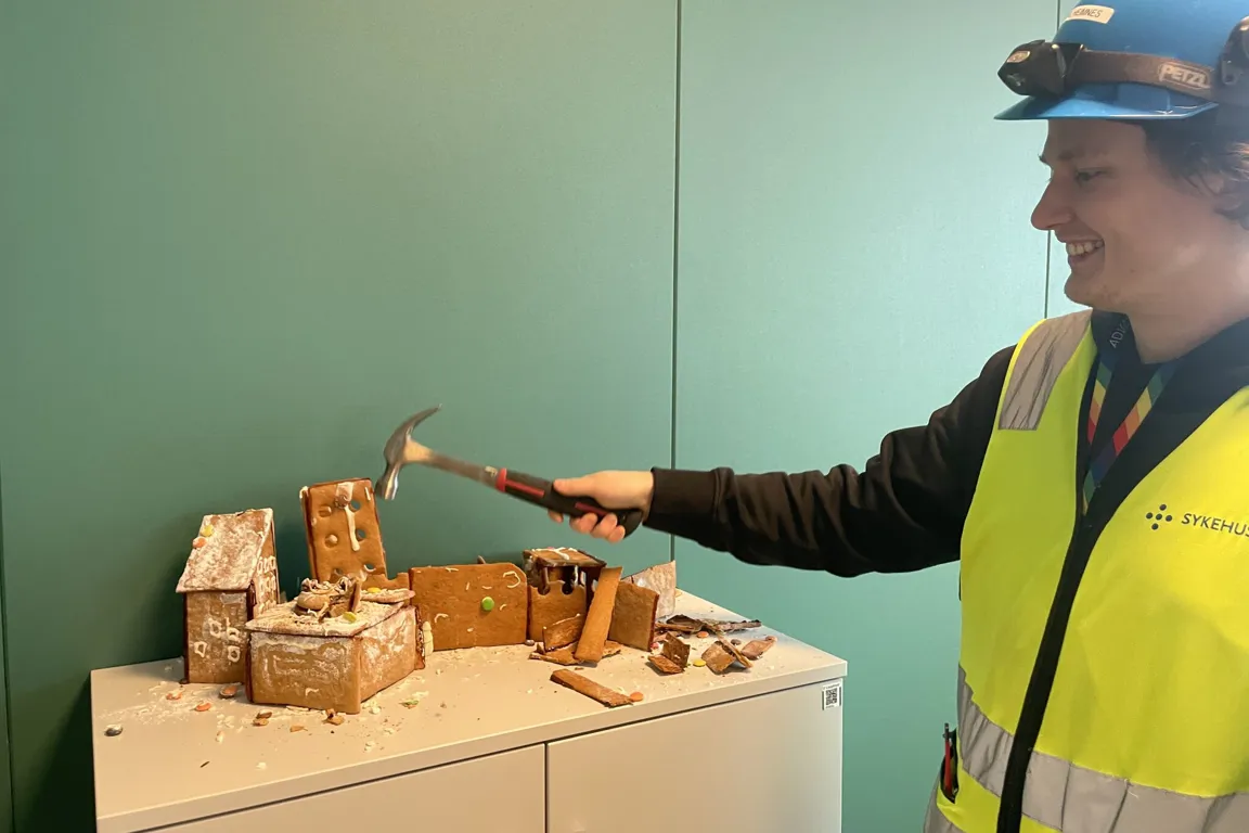 En person i en sikkerhetsvest som holder en hammer og en trekloss