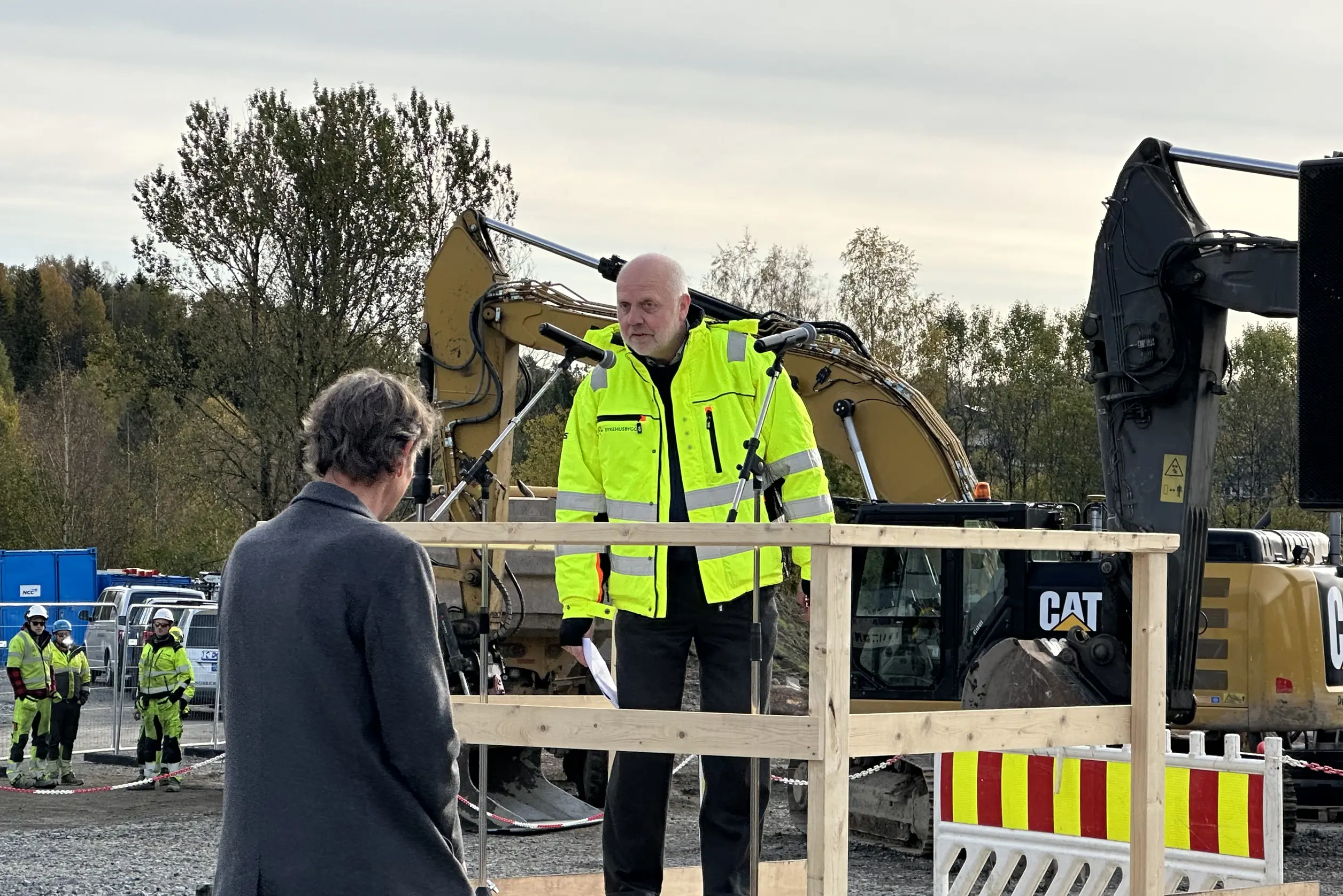 En person i gul jakke som står ved siden av en person i dress