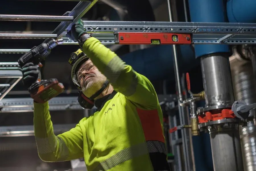 En person i en sikkerhetsvest som jobber på en maskin