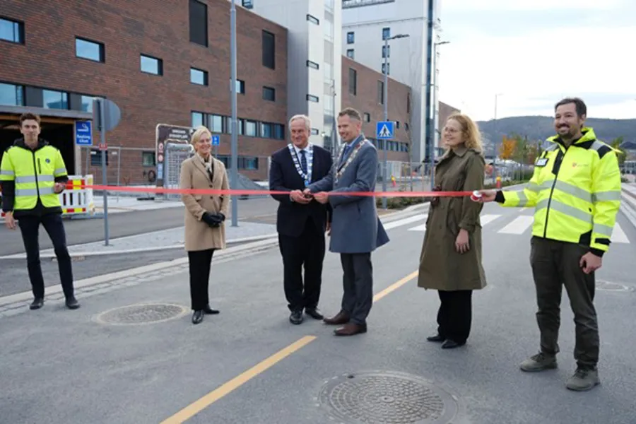 En gruppe mennesker som står på en gate og holder en rød og hvit stang