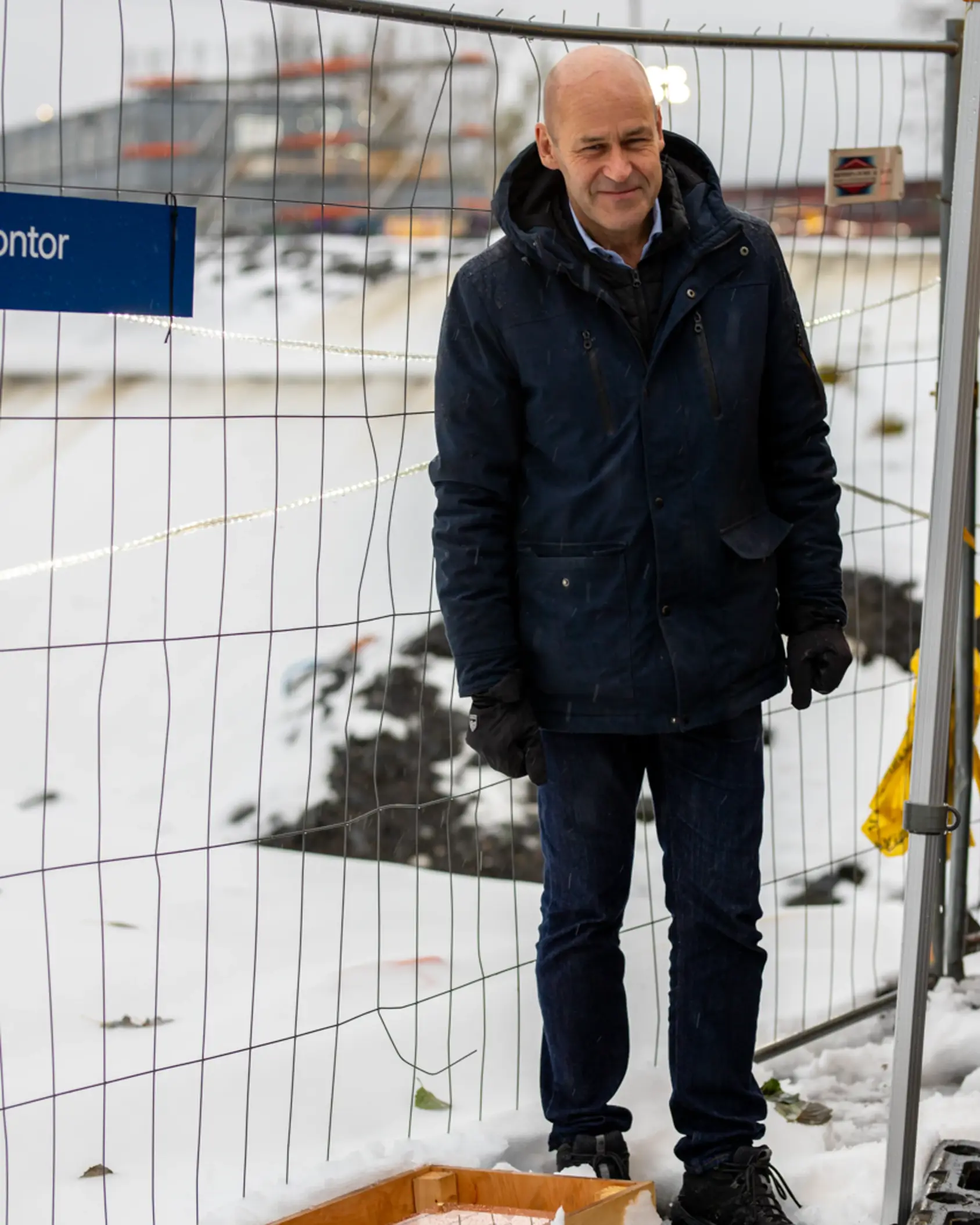 En mann som står foran et gjerde med snø på