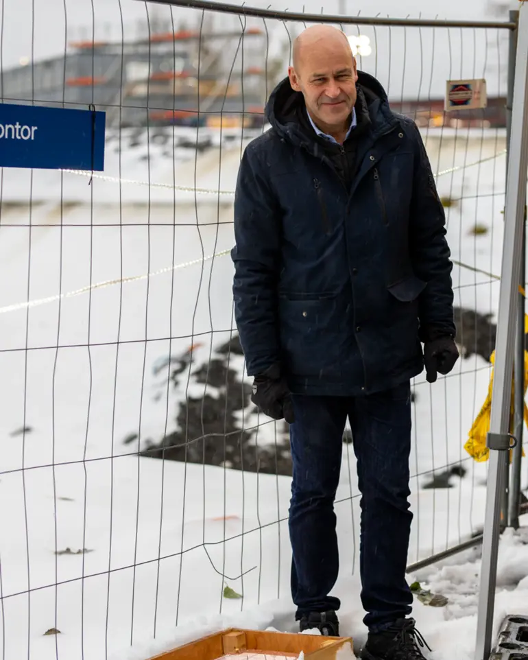 En mann som står foran et gjerde med snø på